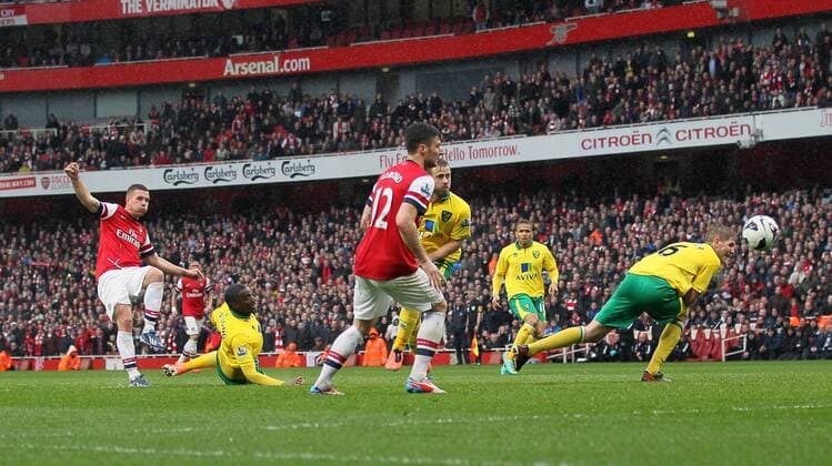 Arsenal s Lukas Podolski scoring his sides third goal.. FC Arsenal London vs Norwich City - Barclays Premier League - Emirates Stadium, London- 12 04 13 - EDITORIAL USE ONLY. No use with unauthorised audio, video, data, fixture lists, club league logos or live services. Online in-match use limited to 120 images, no video emulation. No use in betting, games or single club league player publications.