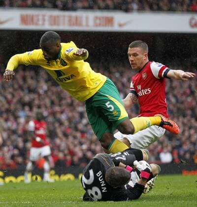 LONDON, April 13, 2013 - Lukas Podolski (Top, R) of Arsenal attacks as Sebastien Bassong (Top, L) of Norwich and his goalie Mark Bunn save the ball during their Barclays Premier League match at the Emirates Stadium in London, Britain, on April 13, 2013. Arsenal won 3-1. (Xinhua Wang Lili) 