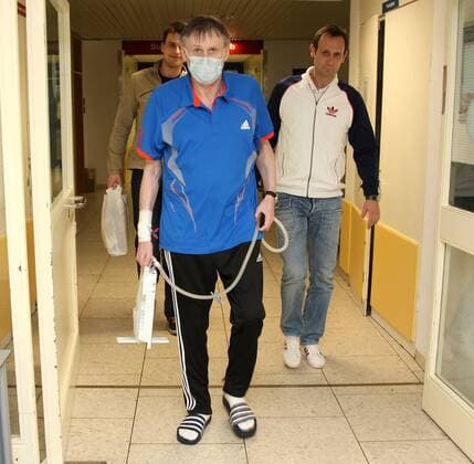 18.04.2013, Hannover, Fussball, 2. Bundesliga, Michael Tönnies nach seiner Lungentransplantation in der MHH in Hannover. Michael Tönnies nach seiner Lungentransplantation mit einem Mundschutz auf dem Gang der Medizinischen Hochschule in Hannover, hinter ihm sein Sohn Marcel (links) und sein Bruder Dirk.