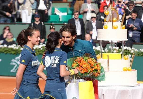 French Open 2013, Roland Garros,Paris,ITF Grand Slam Tennis Tournament, zwei Ballmädchen überreichen Geburtstagskind Rafael Nadal (ESP) eine Blumenstrauss,im Hintergrund steht die riesige Geburtstagstorte Halbkoerper,Querformat,