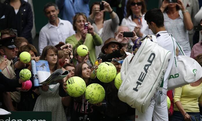 Novak Djokovic of Serbia signs for fans after the first round of men s singles on day 2 of the Wimbledon Lawn Tennis Championships at the All England Lawn Tennis and Croquet Club in London, Britain, on June 25, 2013. 