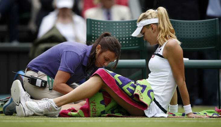 LONDON, July 2, 2013 -- Agnieszka Radwanska (R) of Poland receives the medical treatment during the quarterfinal of women s singles on day 8 of the Wimbledon Lawn Tennis Championships at the All England Lawn Tennis and Croquet Club in London, Britain on July 2, 2013. 