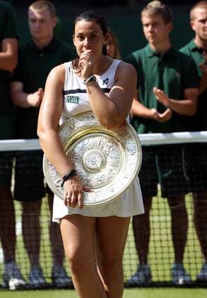 Marion Bartoli of France celebrates winning the title as she climbs into the coaches box, with Amelie Mauresmo and Kristina Mladenovic, at The Championships, Wimbledon, 2013.