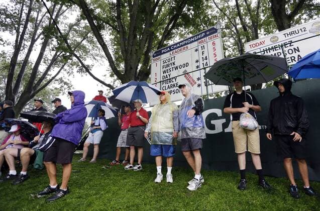 Spectators watch the action on the 13th green while holding umbrellas in the rain in the second round of the PGA Golf Herren Championship at Oak Hill Country Club in Rochester, New York on August 9, 2013.  NYP20130809124