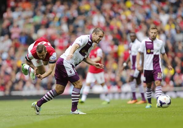 Arsenal s Jack Wilshere gets fouled by Villa s Ron Vlaar - FC Arsenal London v Aston Villa FC - Barclays Premiership - Emirates Stadium - London - England -17 08 2013 - EDITORIAL USE ONLY. No use with unauthorised audio, video, data, fixture lists, club league logos or live services. Online in-match use limited to 120 images, no video emulation. No use in betting, games or single club league player publications.