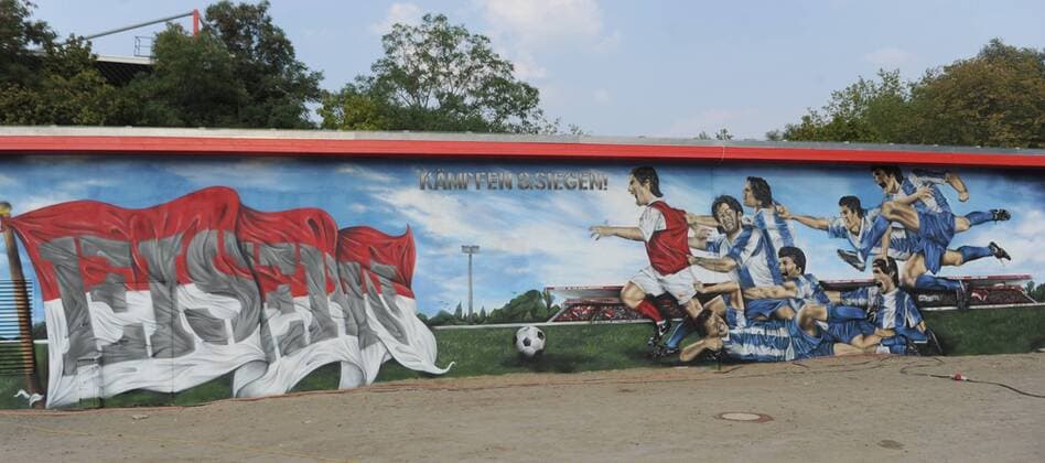 Fussball, Herren, 2. Bundesliga, Saison 2013 2014, 1. FC Union Berlin, Graffiti am Energie-Haus im Stadion An der Alten Försterei am Tag der Fertigstellung, es symbolisiert einen Unioner, der vergeblich von sieben Akteuren von Hertha BSC verfolgt wird, 30.08. 2013,
