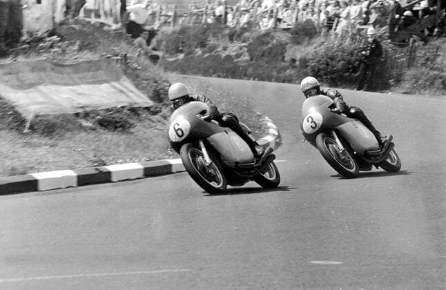 Isle Of Man: Cornering at speed during yesterday s 350 C.c. Junior International t>T. Race here ,are 24 year old Rhodesian Champion, Gary Hocking (left) of Bulawayo, and Mike Hailwood (right) of Oxford, England. Hailwood streaked ahead in the last lap to win from Hocking who was placed second. Both were riding M.V. Augusta machines - Hailwood s time over the six laps was 2 hours 16 minuets 24.2 seconds, with an average speed of 99.59 MPH. 7 June 1962  UnitedArchives00933805