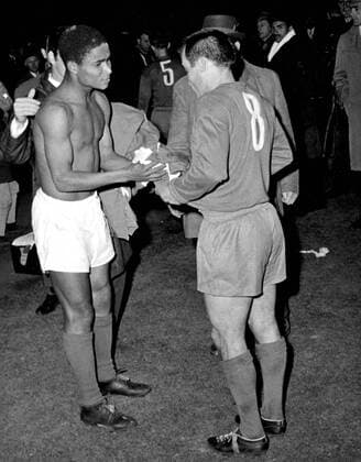 2nd May 1962: The European Cup final. Benfica versus Real Madrid in Amsterdam. Photo shows: Benfica s forward, Da Silva Eusebio (left) pulls off his shirt and presents it to his Real Madrid opposite number, Luis Del Sol, after Benfica had retained the trophy. They beat Real by 5-3. It was the first time that the Madrid club had lost in a final.  UnitedArchives01009406