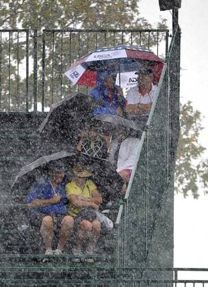 Fans huddle under umbrellas as heavy rain falls during a weather delay in the fourball matches at the 2013 Presidents Cup at Muirfield Village Golf Club in Dublin, Ohio on October 3, 2013.  BKX2013100337