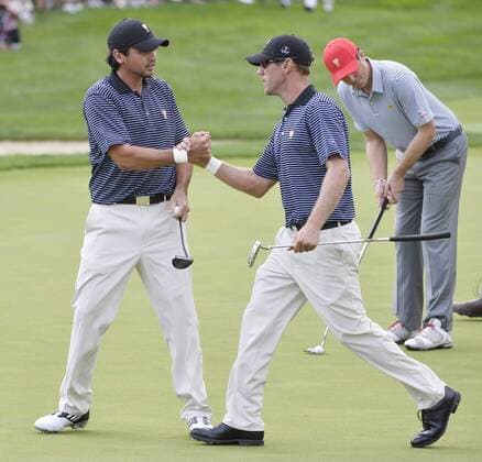 International Team member Graham DeLaet of Canada (R) shakes hands with teammate Jason Day of Australia after Day sunk a birdie putt on the first hole during the second round foursome competition against the United States Team at the 2013 Presidents Cup at Muirfield Village Golf Club in Dublin, Ohio on October 4, 2013.  BKX2013100412