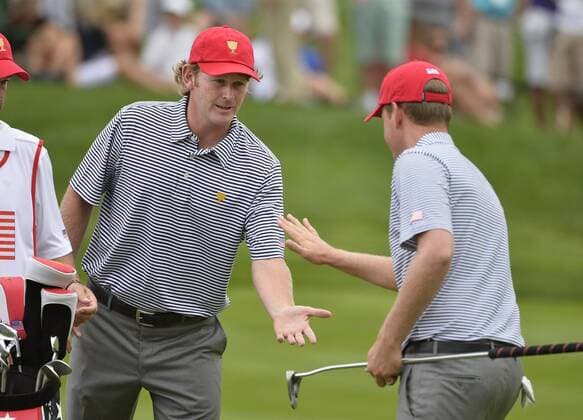 United States Team member Brandt Snedeker (L) congratulates teammate Webb Simpson after Simpson sunk a birdie putt on the fifth hole during the second round foursome competition against the International Team at the 2013 Presidents Cup at Muirfield Village Golf Club in Dublin, Ohio on October 4, 2013.  BKX2013100438