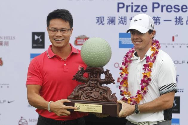 Rory McIlroy of Northern Ireland, right, receives the champion trophy at the award ceremony of The Match at Mission Hills in Haikou city, south Chinas Hainan province, 28 October 2013.  pau902585_18