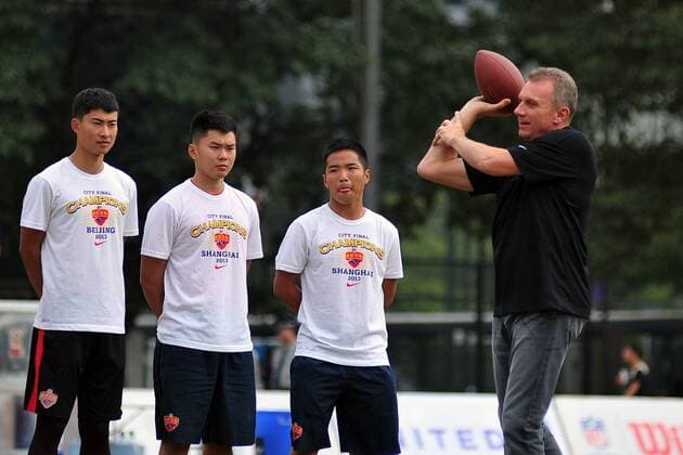 Retired professional American football player Joe Montana, right, shows his American football skill during a promotional event for American football in Guangzhou, south Chinas Guangdong province, 17 November 2013. Joe Montana promotes American football in Guangzhou  20131118_08669
