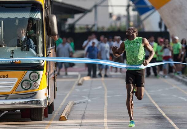The Jamaican record-holder Usain Bolt (R) crosses the finish line after beating a bus in a race in the 9 de Julio Avenue, in Buenos Aires, Argentina, on Dec. 14, 2013. Bolt performed different activities during his visit to Argentina with a talk about leadership, sporting clinics to kids in poverty and a race of 80 meters against a bus in the 9 de julio Avenue. (Xinhua Martin Zabala) (rt) (SP)ARGENTINA-BUENOS AIRES-ATHLETICS-USAIN BOLT 
