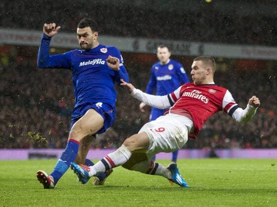 01.01.2014 London, England. Lukas Podolski of Arsenal and Steven Caulker of Cardiff City during the Premier League game between Arsenal and Cardiff City from the Emirates Stadium. Arsenal won the game 2-0. xNigelxCookex  ActionPlus20159925