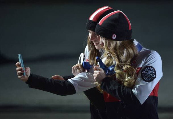 Canada s Chloe Dufour-Lapointe (L) and Justine Dufour-Lapointe take photos of themselves with their medals after a victory ceremony for the Freestyle Skiing Ladies Moguls at the Sochi 2014 Winter Olympics on February 9, 2014 in Sochi. The sisters won silver and bronze respectively.  OLY20140209181