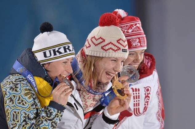 Russia s Olga Vilukhina (R-L), Slovokia s Anastasiya Kuzmina, and Ukraine s Vita Semerenko bite their bronze, gold and silver during their victory ceremony for the Biathalon Women s Sprint at the Sochi 2014 Winter Olympics on February 10, 2014 in Sochi, Russia.  OLY20140210136