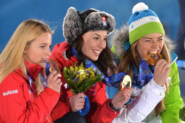 Tying gold medalist, Slovakia s Time Maze, bites her medal as she poses with fellow gold medalist Switzerland s Dominique Gisin and bronze medalist Switzerland s Lara Gut during the victory ceremony for ladies downhill, at the Sochi 2014 Winter Olympics on February 12, 2014 in Sochi, Russia.  OLY20140212365
