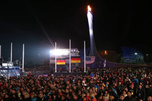 OLYMPIA - Olympische Spiele 2014 SOTSCHI,RUSSLAND,12.FEB.14 - DIVERS, OLYMPIA, RODELN - Olympische Winterspiele Sotschi 2014, Kunstbahnrodeln, Einsitzer der Damen, Medaillenvergabe am Medal Plaza. Bild zeigt die Fahnen und das olympische Feuer. Keywords: Medaille. 
