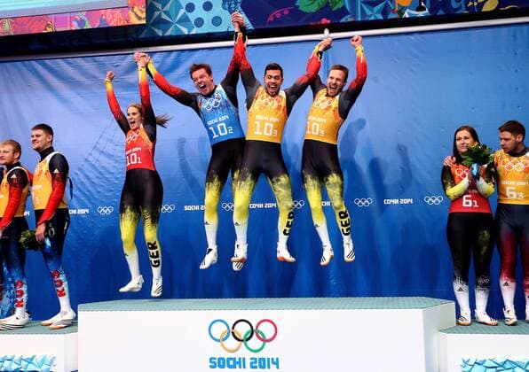 ITAR-TASS: SOCHI, RUSSIA. FEBRUARY 14, 2014. Gold medalists, Germany s Natalie Geisenberger, Felix Loch, Tobias Wendl and Tobias Arlt (L-R center) jump at a flower ceremony following the Luge Team Relay competition at the 22nd Winter Olympic Games in Sochi, at the Sanki Sliding Center.  Highlight RE1392D3