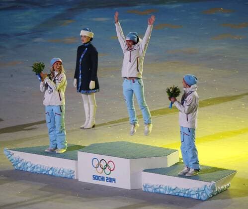 Norway s Marit Bjoergen (C) leaps into the air as she is announced as the gold medal winner for the ladies 30km cross-country skiing max start race during the Closing Ceremony at the Sochi 2014 Winter Olympics on February 23, 2014 in Sochi, Russia. With Bjoergen on the podium are teammates Therese Johaug (L) who won the silver and Kristin Stoermer Steira who won bronze.  OLY20140223131
