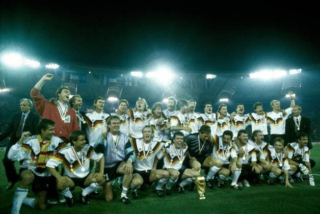 Weltmeisterschaft 1990. Die Deutsche Mannschaft mit WM Pokal nach dem Sieg im Finale am 8.7. in Rom, hi.v.li.: Holger Osieck, Franz Beckenbauer, Klaus Augenthaler, Stefan Reuter, Jürgen Klinsmann, Frank Mill, Guido Buchwald, Karl Heinz Riedle, Paul Steiner, Thomas Berthold, Andreas Köpke, Jürgen Kohler, Andreas Möller, Hansi Pflügler, Berti Vogts, vorn: Pierre Littbarski, Olaf Thon, Sepp Maier, Andreas Brehme, Lothar Matthäus, Bodo Illgner, Uwe Bein, Günter Hermann, Rudi Völler, Thomas Häßler, Raimond Aumann HM
