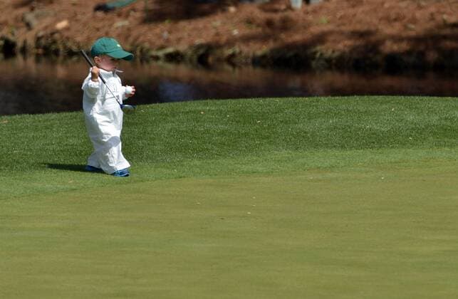 Scott Staulings son Finn carries a mini golf club as he walks on the eighth green during the Par 3 Contest during the Masters Tournament at Augusta National Golf Club in Augusta, Georgia, April 8, 2014.  AUG20140409350