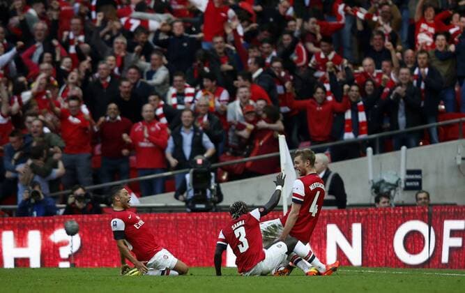 Per Mertesacker (R) of Arsenal celebrates scoring during FA Cup semifinal match between Arsenal FC and Wigan Athletic at Wembley Stadium in London, Britain, on April 12, 2014. (Xinhua Wang Lili) 