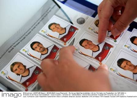 Ein Junge klebt Sammelbilder mit den Portraits von Fussballern der WM 2014 in Brasilien in ein Panini Sammelalbum - Julian Draxler ( Schalke 04 - Deutschland ) Panini Sammelbilder