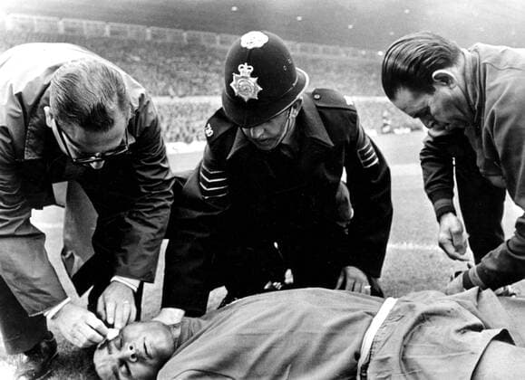 1966 World Cup Portugal v Hungary. Portugal s Eusebio is pictured receiving attention from officials and a policeman, after he was injured during the match. Portugal won 3-1. 13th July 1966, Polizei, Polizist, Polizeimann kbdig quer  UnitedArchives00598317
