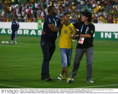 ITAR-TASS: CAMPINAS, BRAZIL. JUNE 13, 2014. Security guards escort a fan off the field at a training session of the Nigerian national football team at Guarani Stadium during the 2014 FIFA World Cup.  RE147292