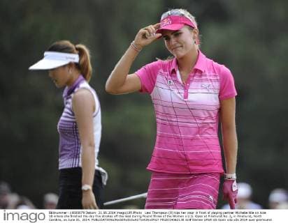 Lexi Thompson (R) tips her visor in front of playing partner Michelle Wie on hole 18 where she finished the day five strokes off the lead during Round Three of the Women s U.S. Open at Pinehurst No. 2, in Pinehurst, North Carolina, on June 21, 2014.  PIN2014062138