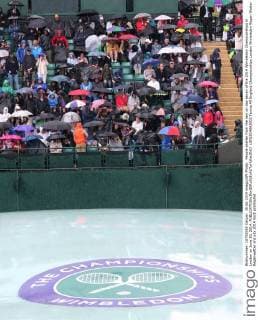 People shelter from the rain on day seven of the 2014 Wimbledon Championships in London on June 30, 2014.  LON2014063003