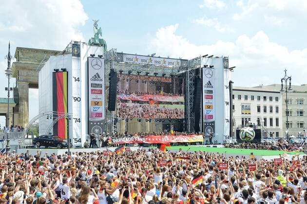 Empfang der Weltmeister --- Fussball --- International --- 15.07.2014 Die deutsche Nationalmannschaft präsentiert ein Banner mit der Aufschrift: Obrigado Fans! Der 4. Stern ist unser!, im Hintergrund das Brandenburger Tor, davor jubelnde Fans, Anhänger, Anhaenger, Groupies, Zuschauer, Jubel, Freude, Mannschaft, Team, Feature