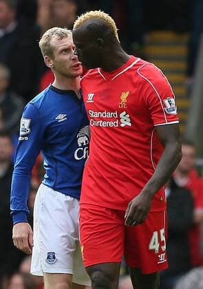 Mario Balotelli of Liverpool and Tony Hibbert of Everton clash - Barclays Premier League - Liverpool vs Everton - Anfield Stadium - Liverpool - England - 27th September 2014 - EDITORIAL USE ONLY. No use with unauthorised audio, video, data, fixture lists, club league logos or live services. Online in-match use limited to 120 images, no video emulation. No use in betting, games or single club league player publications.