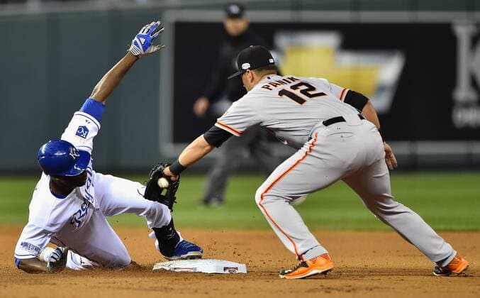 Kansas City Royals center fielder Lorenzo Cain (L) reaches second before the tag by San Francisco Giants second baseman Joe Panik for a double in the first inning of game 2 of the World Series at Kaufman Stadium in Kansas City, Missouri on October 22, 2014. San Francisco holds a 1-0 series lead over Kansas City.  KCP2014102214