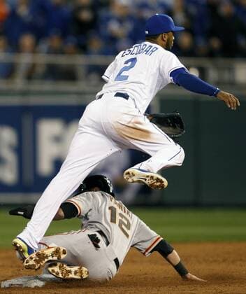 Kansas City Royals shortstop Alcides Escobar leaps over San Francisco Giants second baseman Joe Panik completing a double play to end a bases loaded Giants scoring threat in the fifth inning of game 6 of the World Series at Kaufman Stadium in Kansas City, Missouri on October 22, 2014. San Francisco leads the series 3-2 over Kansas City.  KCP2014102863