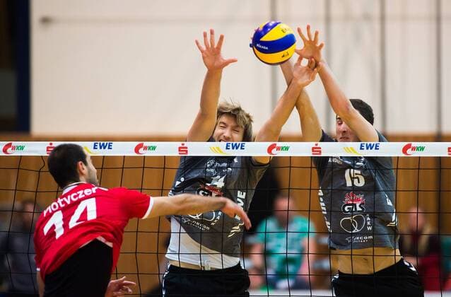 Bestensee, Deutschland, 26.11.2014: Volleyball Bundesliga Saison 2014 2015 - Netzhoppers KW - TV Buehl Bühl. Mark Plotyczer (Buehl) gegen den Block aus Paul Sprung (Netzhoppers 14) und Georg Escher (Netzhoppers 15)