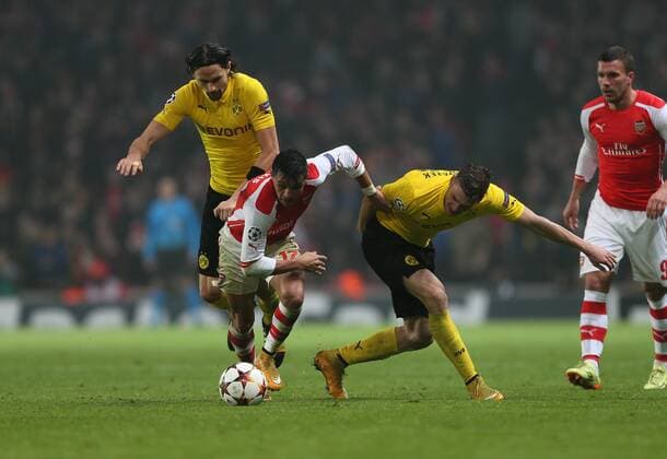 Arsenal s Alexis Sanchez tussles with Dortmund s Neven Subotic and Kevin Grosskreutz UEFA Champions League- Arsenal vs Borussia Dortmund- Emirates Stadium - England - 26th November 2014 - EDITORIAL USE ONLY. No use with unauthorised audio, video, data, fixture lists, club league logos or live services. Online in-match use limited to 120 images, no video emulation. No use in betting, games or single club league player publications.