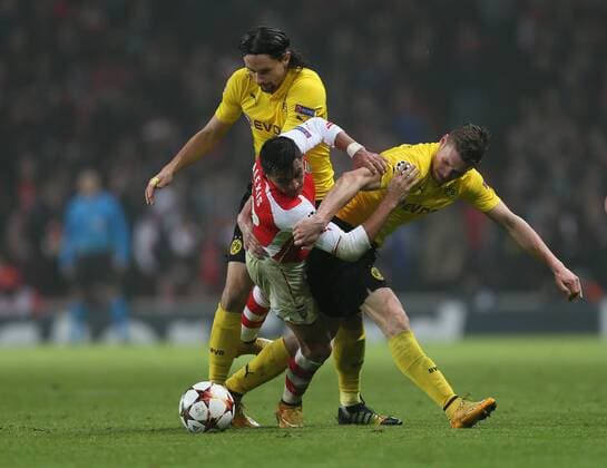 Arsenal s Alexis Sanchez tussles with Dortmund s Neven Subotic and Kevin Grosskreutz UEFA Champions League- Arsenal vs Borussia Dortmund- Emirates Stadium - England - 26th November 2014 - EDITORIAL USE ONLY. No use with unauthorised audio, video, data, fixture lists, club league logos or live services. Online in-match use limited to 120 images, no video emulation. No use in betting, games or single club league player publications.