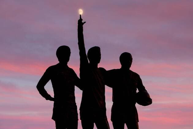 The Holy Trinity statue of George Best, Denis Law and Sir Bobby Charlton is seen below the moon at sunset over Old Trafford - Manchester United ManU EDITORIAL USE ONLY. No use with unauthorised audio, video, data, fixture lists, club league logos or live services. Online in-match use limited to 120 images, no video emulation. No use in betting, games or single club league player publications.