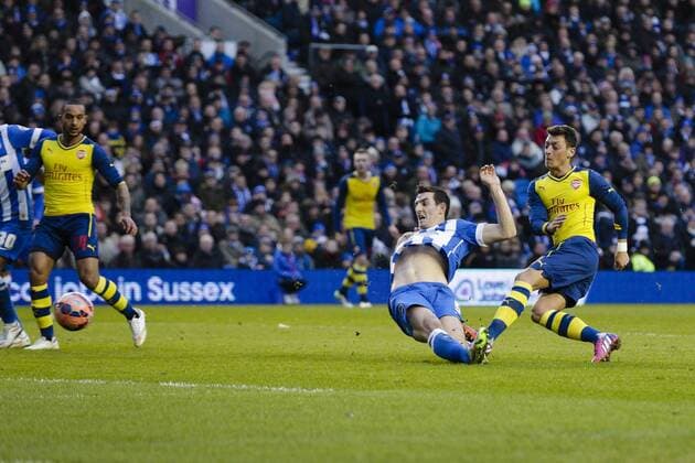 25.01.2015. Brighton, England. FA Cup 4th Round. Brighton and Hove Albion vs Arsenal FC. Arsenal s Mesut Ã–zil scores the second goal to make it 0-2, despite the lunging tackle of Brighton and Hove Albion s Lewis Dunk xCraigxMercerx  ActionPlus11592464