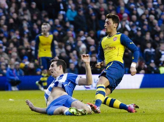 25.01.2015. Brighton, England. FA Cup 4th Round. Brighton and Hove Albion vs Arsenal FC. Arsenal s Mesut Ã–zil scores the second goal to make it 0-2, despite the lunging tackle of Brighton and Hove Albion s Lewis Dunk xCraigxMercerx  ActionPlus11592465