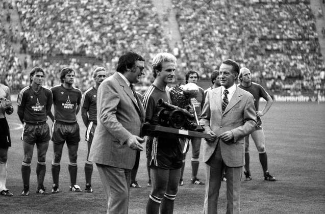 FC Bayern München - Borussia Dortmund: Karl-Heinz Rummenigge (mi.) erhält die Torjägerkanone und die Auszeichnung zum Fußballer des Jahres - es gratulieren Präsident Willi O. Hoffmann (li., beide Bayern) und Kicker-Chefredakteur Karl-Heinz Heimann