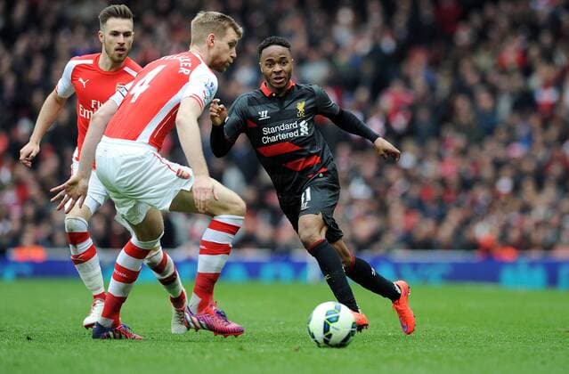 Raheem Sterling of Liverpool is challenged by Per Mertesacker of Arsenal - Barclays Premier League - Arsenal vs Liverpool - Emirates Stadium - London - England - 4th April 2015 - Pic Robin Parker Sportimage EDITORIAL USE ONLY. No use with unauthorised audio, video, data, fixture lists, club league logos or live services. Online in-match use limited to 120 images, no video emulation. No use in betting, games or single club league player publications. TM3_8401.JPG