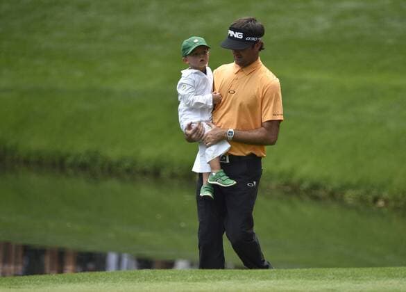 Bubba Watson caries his son Caleb as they walk onto the 9th green during the Par 3 contest at the 2015 Masters Tournament at Augusta, National in Augusta, Georgia on April 8, 2015.  AUG20150408368 KEVINxDIETSCH