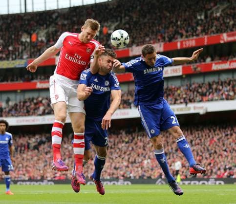 Arsenal s Per Mertesacker tussles with Chelsea s Gary Cahill and Nemanja Matic Barclays Premier League - Arsenal vs Chelsea - Emirates Stadium - England - 26th April 2015 - Picture David Klein Sportimage EDITORIAL USE ONLY. No use with unauthorised audio, video, data, fixture lists, club league logos or live services. Online in-match use limited to 120 images, no video emulation. No use in betting, games or single club league player publications.