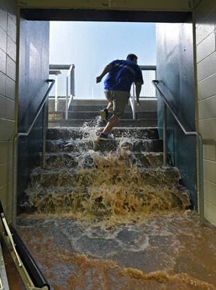 July 6, 2015 - Kansas City, MO, USA - A member of the Kansas City Royals tarp crew bolts up the dugout steps to open a clogged drain as water pours in during a storm that canceled the baseball game against the Tampa Bay Rays on Monday, July 6, 2015, at Kauffman Stadium in Kansas City, Mo. Tampa Bay Rays at Kansas City Royals game rained out - ZUMAm67_