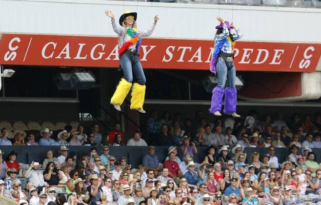 Calgary, Alberta; Canada--- Two rodeo barrel racers are lowered on cables during cowboy and cowgirl introductions for the rodeo at the Calgary Stampede. digital photo by Larry MacDougal