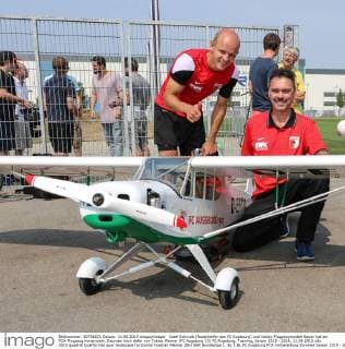 Josef Schmidt (Rasenhelfer des FC Augsburg) und Hobby-Flugzeugmodell-Bauer hat ein FCA-Flugzeug konstruiert. Daumen hoch dafür von Tobias Werner (FC Augsburg 13) FC Augsburg, Training, Saison 2015 - 2016, 11.08.2015